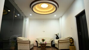 A room with a sofa, two armchairs, a small table, and a Buddha statue. - Hotel Shivani International (Dharamshala)