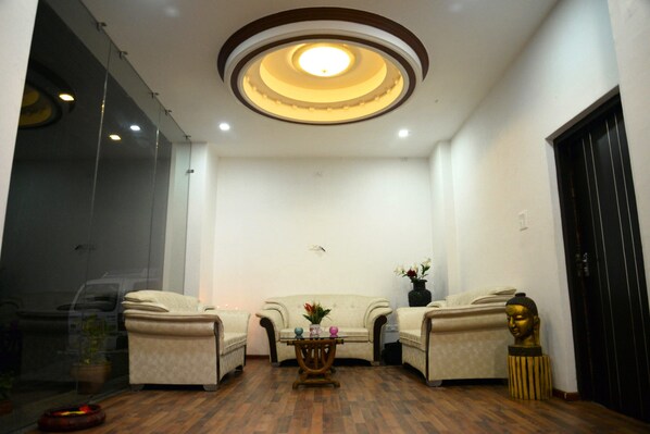 A room with a sofa, two armchairs, a small table, and a Buddha statue.