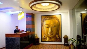 A reception area with a Buddha statue, a receptionist desk, and a modern ceiling design. - Hotel Shivani International (Dharamshala)