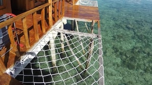 A wooden deck with a netted area, clear water, and a distant island. - Ora Sunrise View Resort (Salemang)