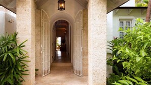 A corridor with white doors, a light fixture above, and plants on either side.