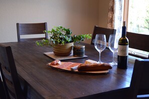 Enjoy a casual meal at this inviting dining table, complete with a potted plant, wine, and a selection of bread and meats.