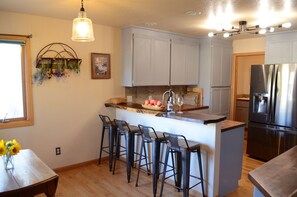 Enjoy casual dining at the central island with bar stools, featuring a refrigerator, oven, and sink with a farmhouse-style faucet.
