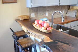 Eine Küche mit einer Holzausziehtafel, einer Spüle und einem Korb voller Äpfel.