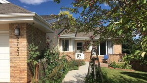 Une maison d’habitation avec une façade en briques, un portail de garage visible et une cour avant avec un chemin menant à l’entrée.