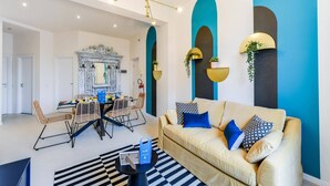 A modern living room with a sofa, chairs, a dining table, and a decorative mirror.