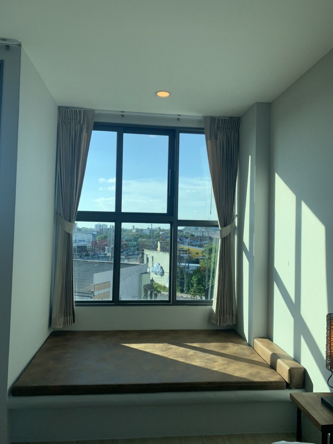 A room with a large window, a built-in bench, and a view of a cityscape.
