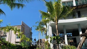 A modern hotel with a pool area, palm trees, and outdoor seating. - Atom Phuket Hotel (Sa Khu)