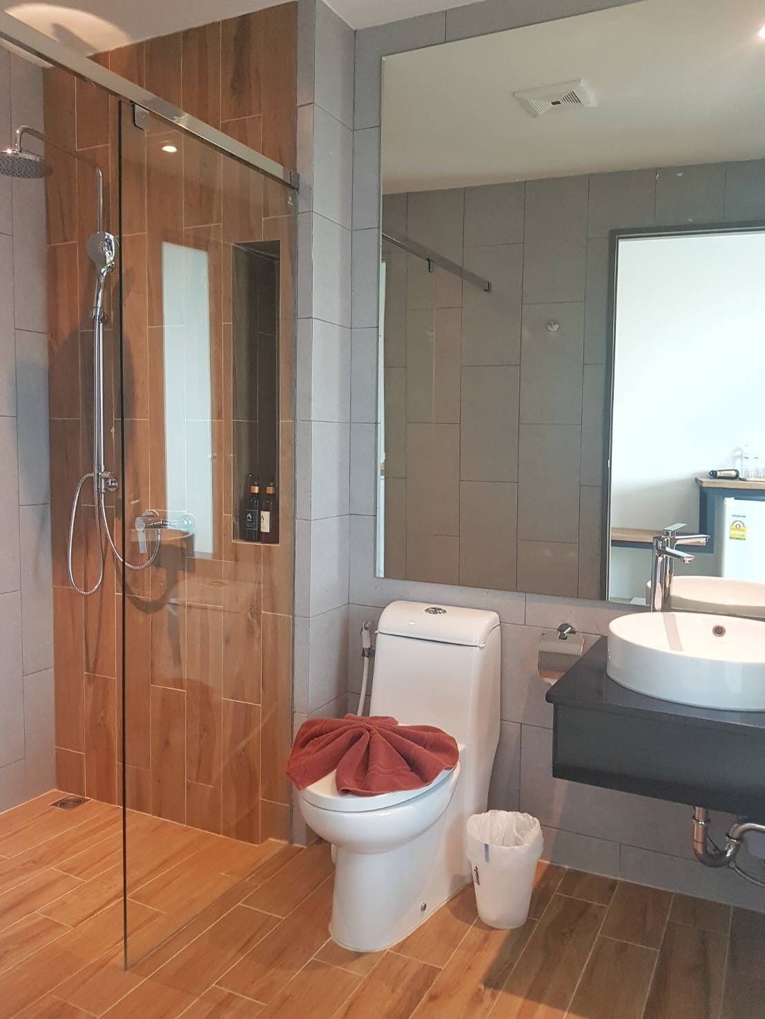 A modern bathroom with a glass-enclosed shower, a toilet, and a sink with a mirror above it.