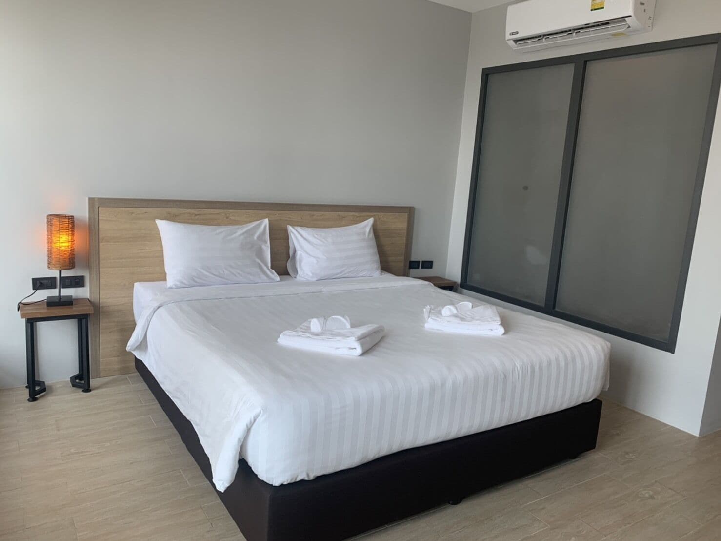Ein modernes Hotelzimmer mit einem großen Bett, einer Nachttischlampe und einer Klimaanlage.