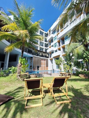A modern hotel with a pool, palm trees, and outdoor seating. - Atom Phuket Hotel (Sa Khu)