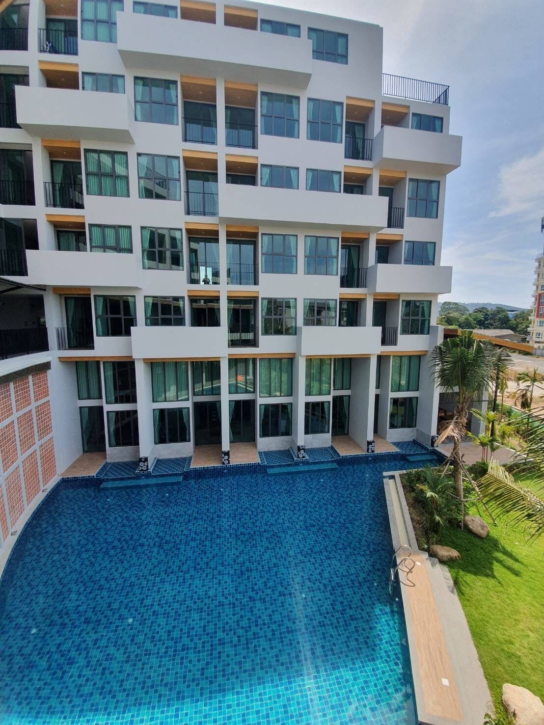 A modern multi-story hotel with a large pool area.