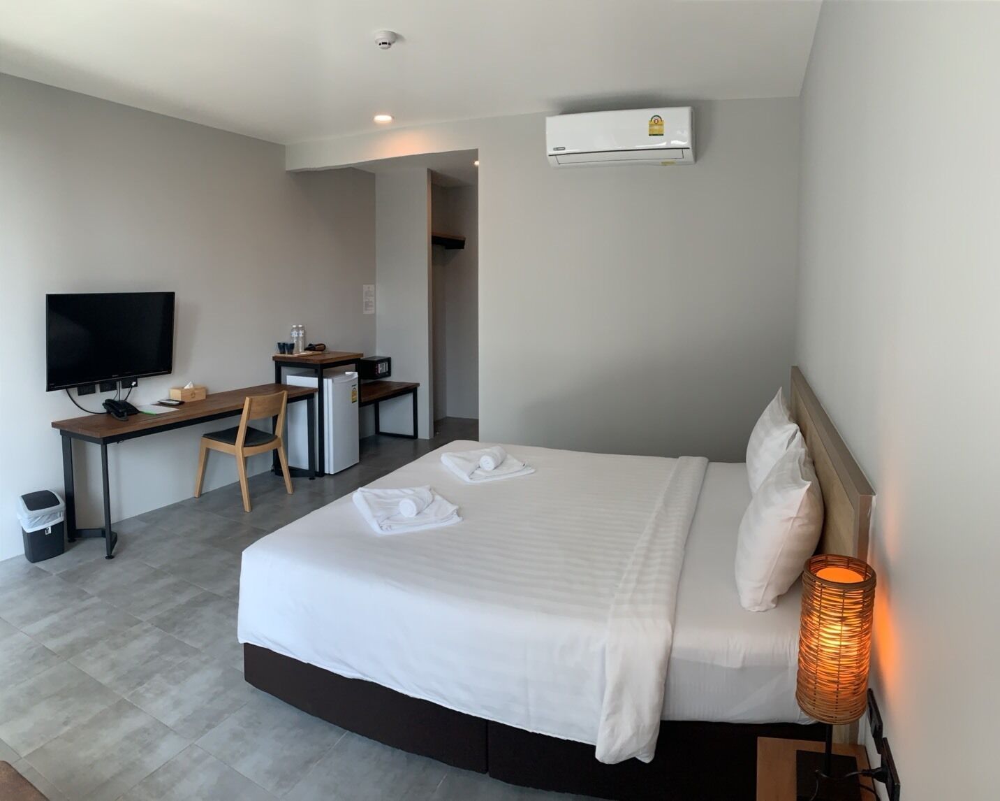 Ein Hotelzimmer mit Bett, Schreibtisch, Stuhl, Fernseher und Klimaanlage.