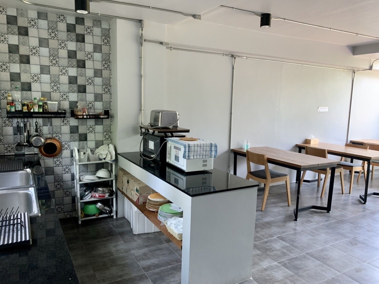 Une cuisine moderne avec un dosseret à carreaux, un îlot central doté d’appareils électroménagers et un coin repas avec des tables et des chaises en bois.