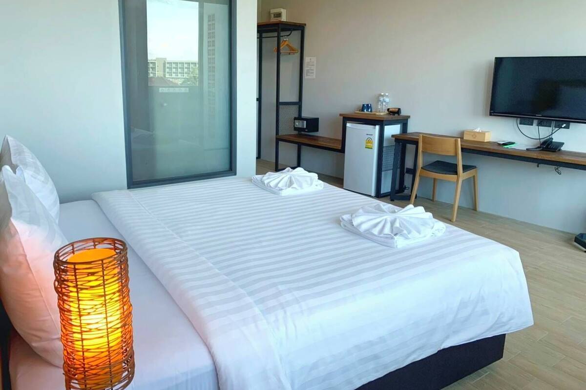 Una habitación de hotel con cama, escritorio, televisor y ventana.