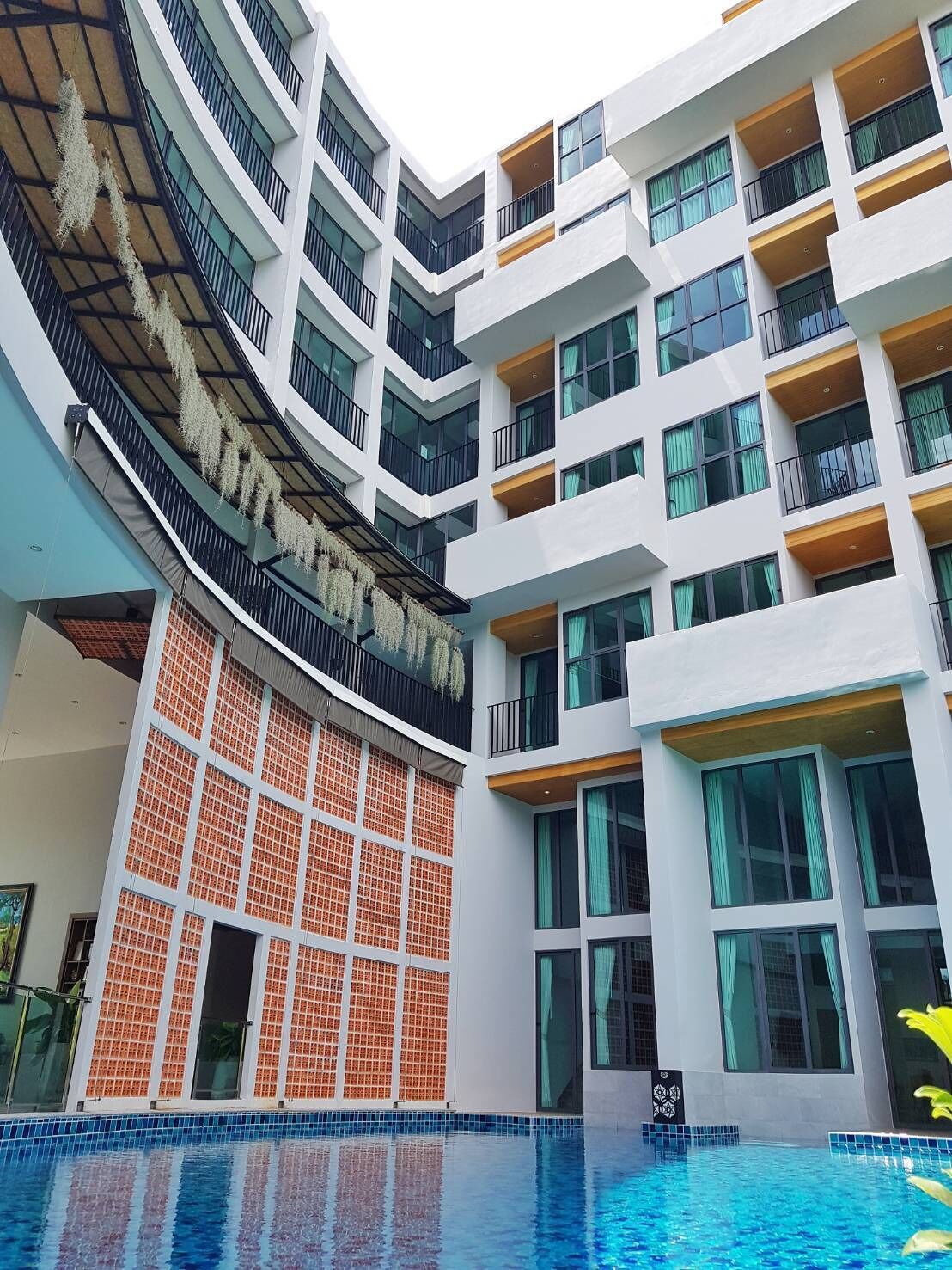 A modern hotel with multiple floors, balconies, and a swimming pool.