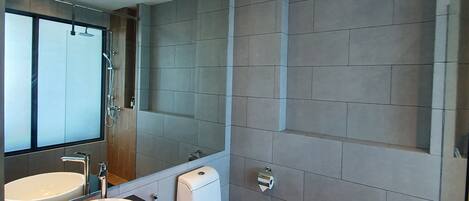 Un baño moderno con un espejo grande, un lavabo redondo, un inodoro y una ducha.