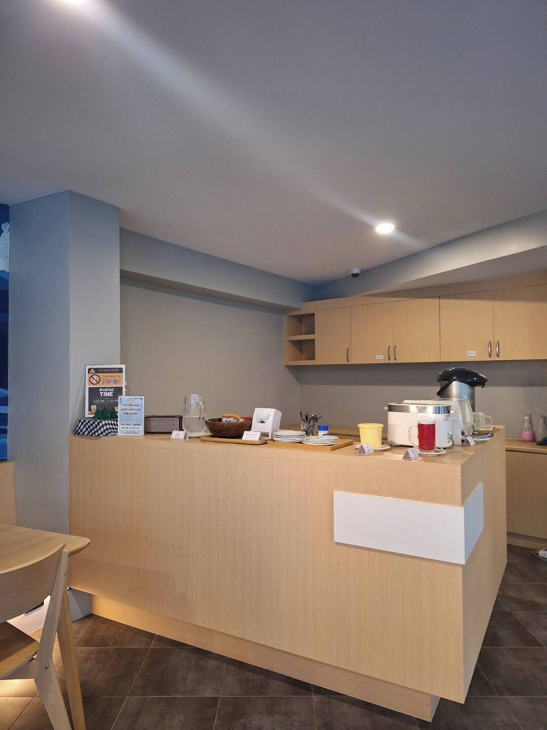 Une cuisine moderne dotée d’un bar pour prendre le petit-déjeuner, de meubles de rangement en bois et d’une machine à café.