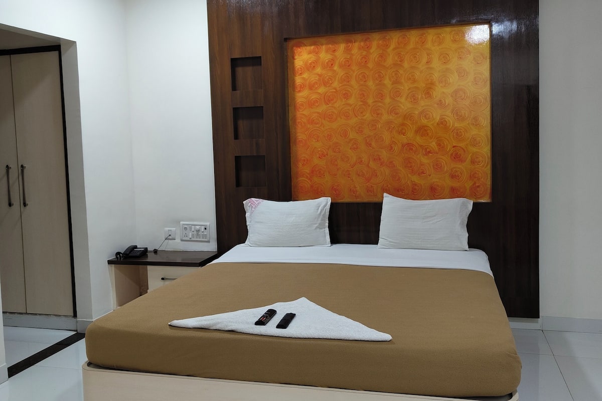 Een hotelkamer met een bed, een nachtkastje met een telefoon, een plafondventilator en een groot muurschilderij.