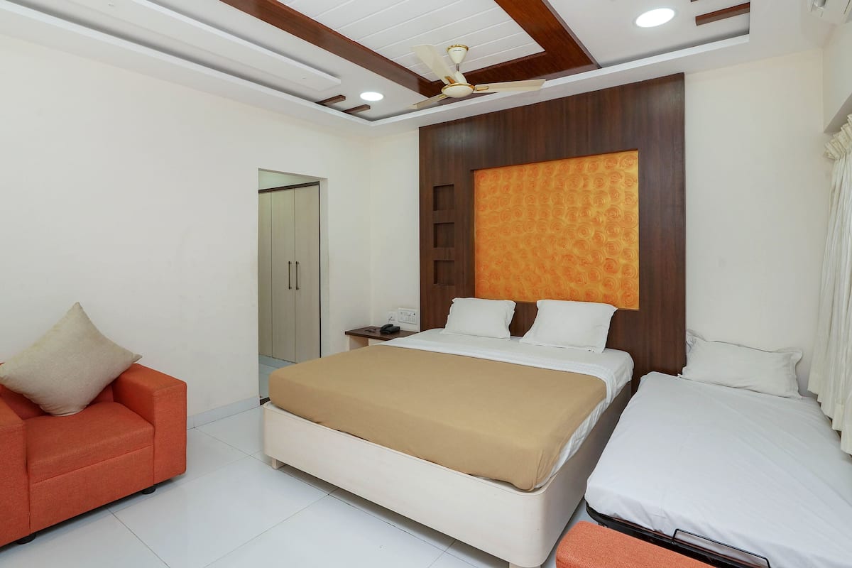 Een moderne slaapkamer met een bed, een bank, een nachtkastje en een plafondventilator.