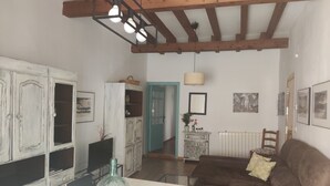 A living room with a brown sofa, a glass-top table, and a cabinet with a basket on top. - Wonderful apartment in the Jewish quarter (Segovia)