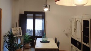 A dining area with a wooden table, chairs, a hanging light fixture, and a cabinet with open doors. - Wonderful apartment in the Jewish quarter (Segovia)