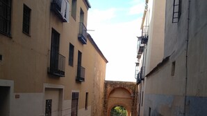 A narrow cobblestone street flanked by buildings with balconies and an archway at the end. - Wonderful apartment in the Jewish quarter (Segovia)