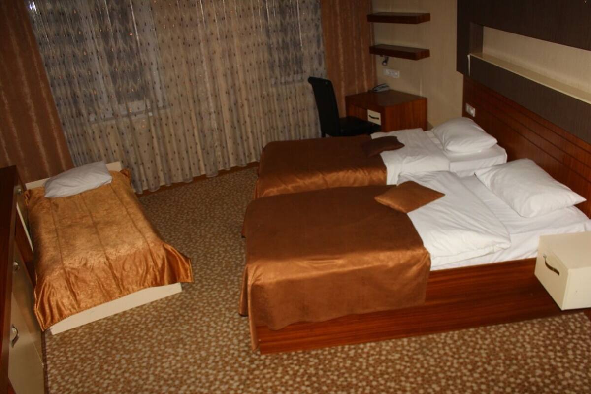 A hotel room with two beds, a desk, and a chair.