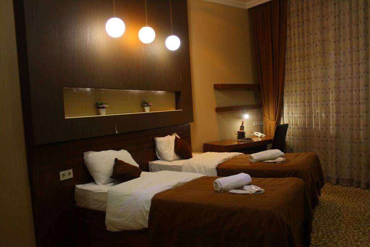 A hotel room with two beds, a desk, and a mirror.