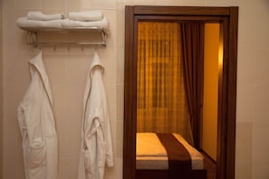 A hotel room with a bed, a wooden door, and two towels hanging on a rack.