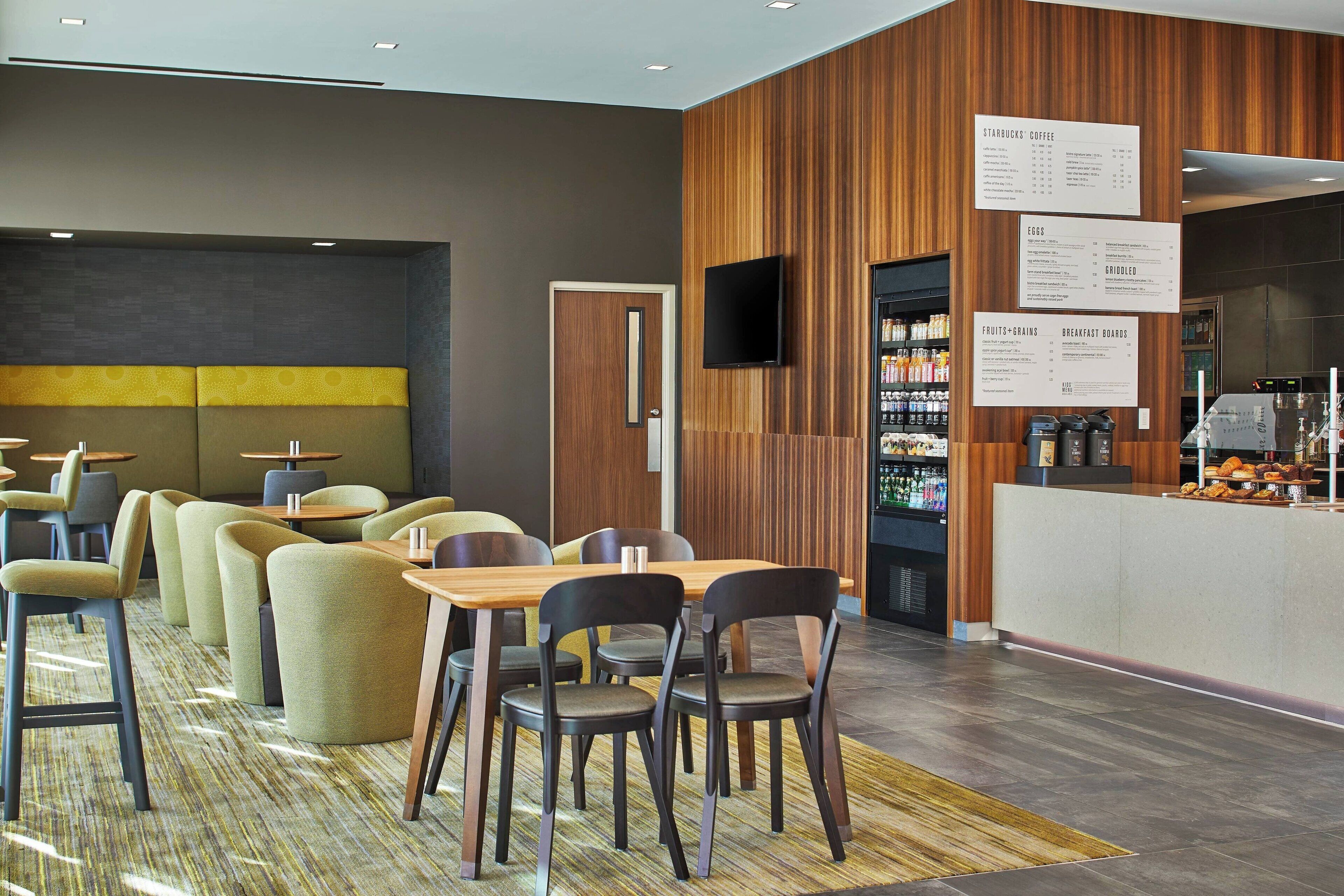 Un comedor moderno con paneles de madera, una pizarra de menú y una estación de bebidas.