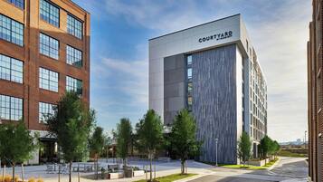 A Courtyard by Marriott hotel with a modern design, featuring a large glass facade and a courtyard with trees and seating areas.