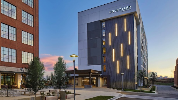 A Courtyard by Marriott hotel with a modern facade, large windows, and a well-lit entrance area.