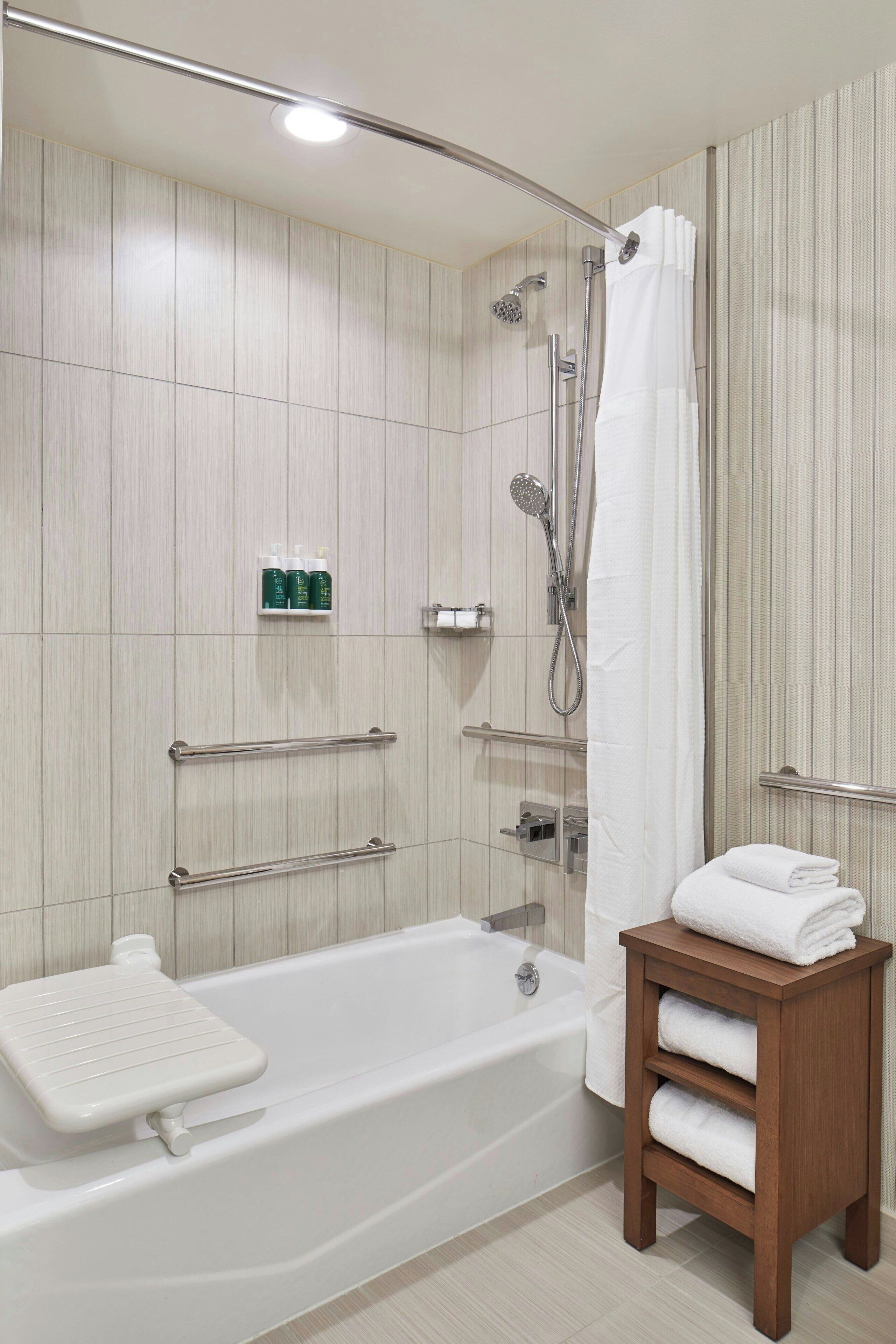 Un baño moderno con bañera, ducha y un mueble de tocador de madera con toallas.