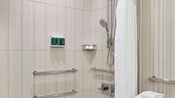 Un baño moderno con bañera, ducha y un mueble de tocador de madera con toallas.