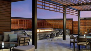 An outdoor patio with a fire feature, seating, and a view of the sky.
