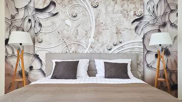 A bedroom with a large bed, two bedside lamps, and a wall with floral and abstract designs.