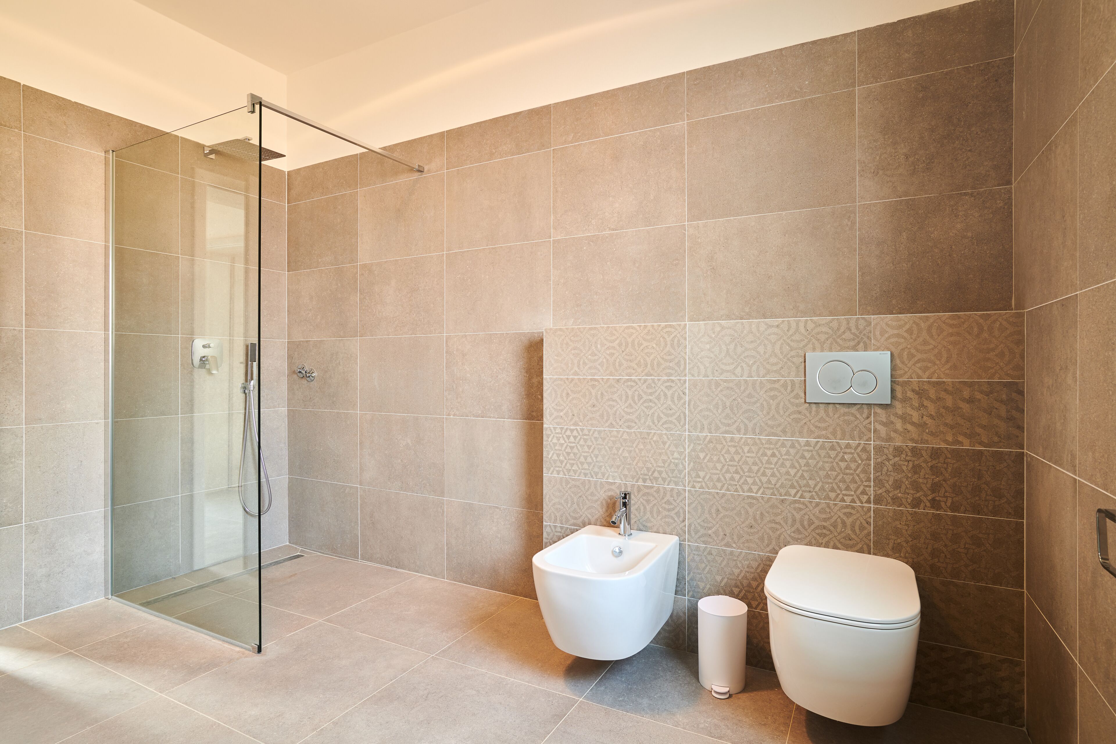Ein modernes Badezimmer mit Duschkabine aus Glas, einem Bidet und einer Toilette.