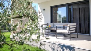 Un espace extérieur moderne aménagé avec un canapé et une table, un mur en pierre et une porte vitrée donnant sur un patio couvert.