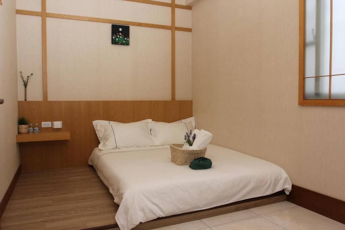 Une chambre d’hôtel bien rangée, avec un lit, une petite étagère contenant des articles de toilette et un tableau accroché au mur.