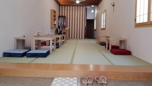 Perinteinen japanilaistyylinen huone, jossa on tatamimatto, matalat puupöydät ja tyynyt.