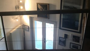 Une pièce avec un radiateur, une porte donnant sur un beau paysage et plusieurs tableaux encadrés accrochés au mur.