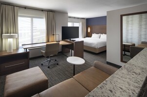 Habitación de hotel con cama, escritorio con silla, televisión, pequeña mesa y sofá.