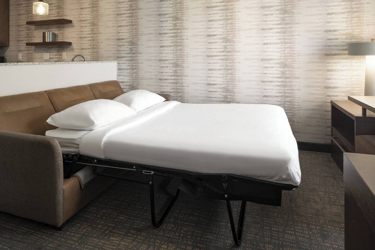 A hotel room with a bed, a desk, and a chair.