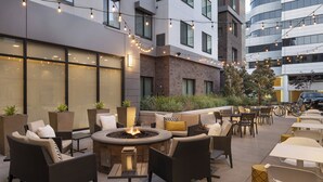 An outdoor seating area with wicker furniture, a central fire feature, and string lights. - Residence Inn by Marriott Walnut Creek (Walnut Creek)