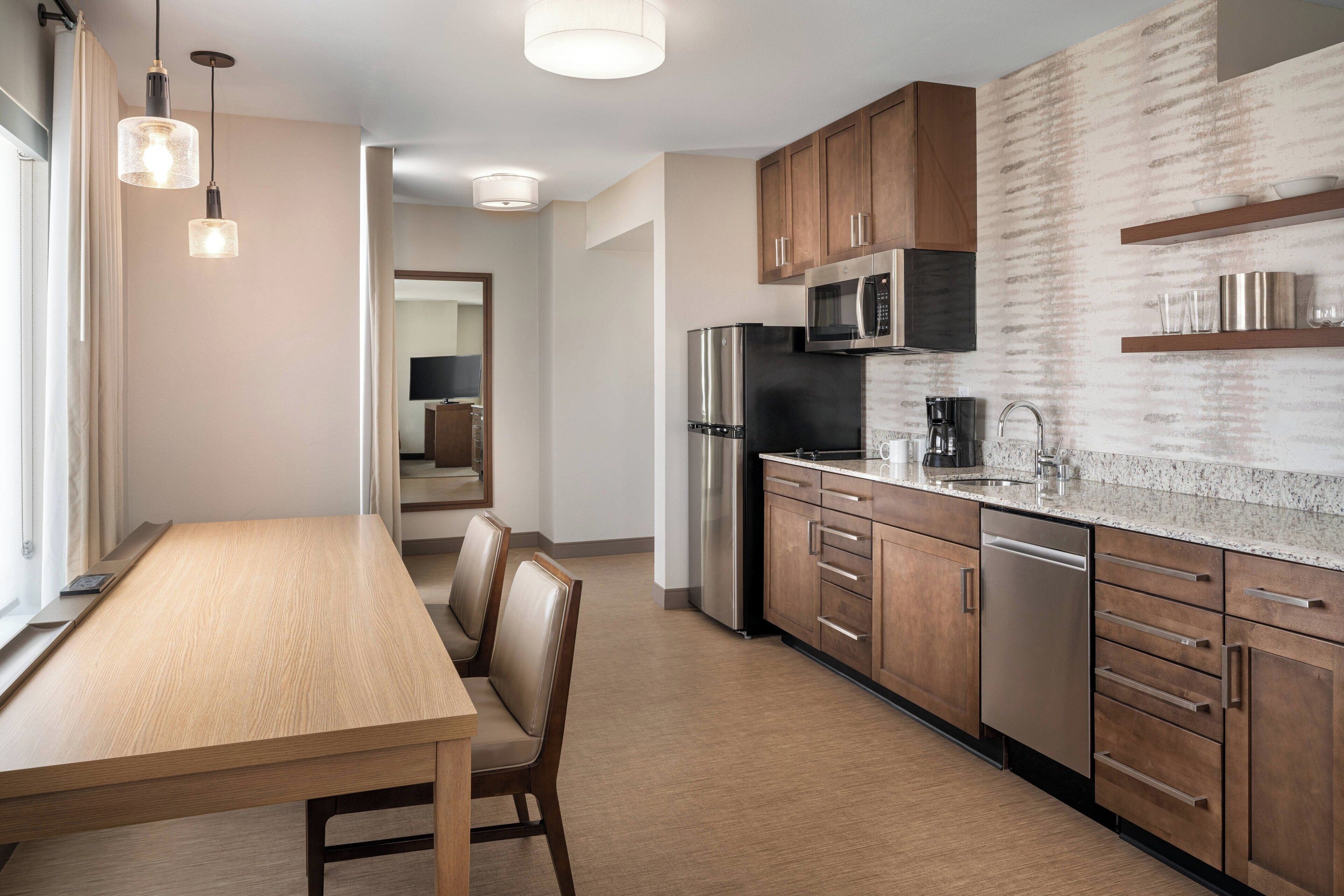 A modern kitchen with wooden cabinets, stainless steel appliances, and a granite countertop.