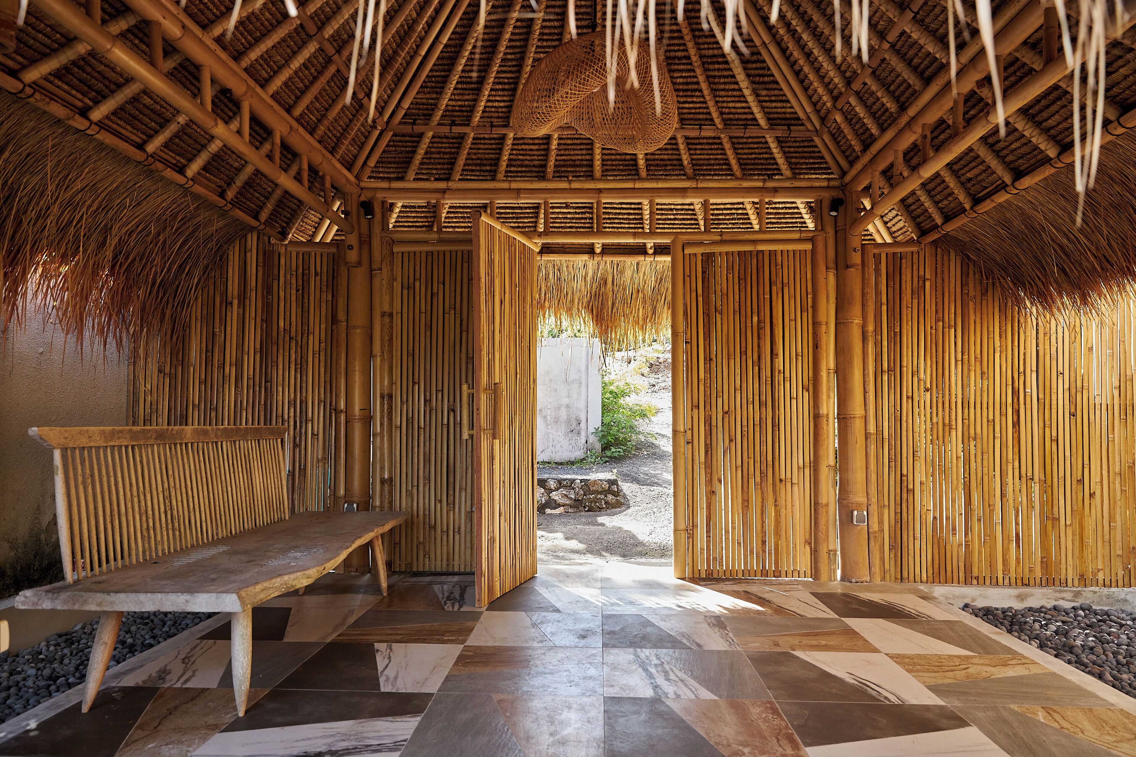 Egy kockás mintájú padlószakasz, egy pad és bambuszból készült falak találhatók a szobában.