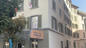 A building with a sign for 'Mamma Mia' restaurant and pizzeria, featuring a stone facade and a cobblestone street. - Altstadtwohnung (Chur)