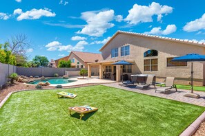 A backyard with a swimming pool, a patio with outdoor furniture, and a well-maintained lawn.