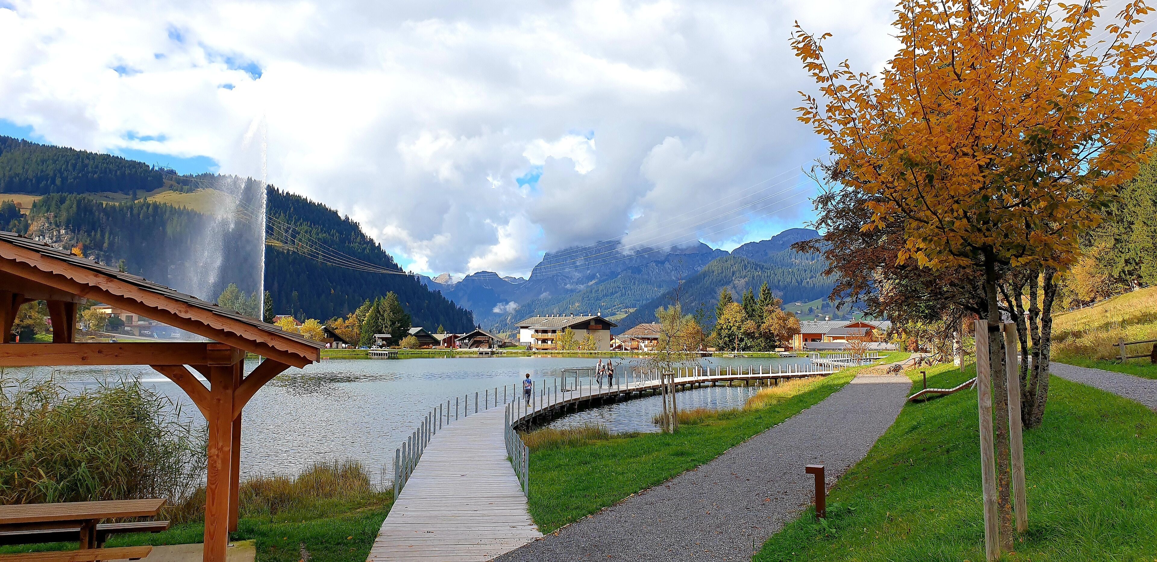 A wooden pier leading to a lake with a mountain backdrop.